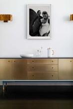 Load image into Gallery viewer, Euphoria Waves by Addison Jones Studio - a powerful black-and-white image featuring a female surfer with a surfboard, displayed creatively in a cozy living space.