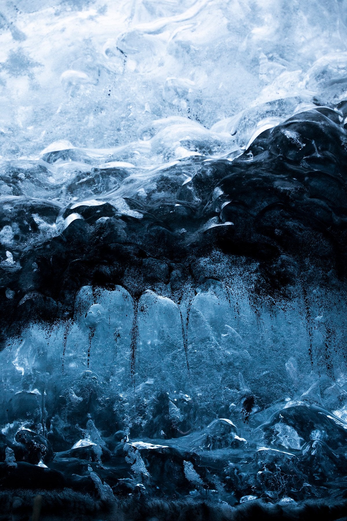 Close-up view of icy textures and formations, highlighting beautiful shades of blue and black in the permafrost. Perfect example of Iceland wall art from Addison Jones Studio.