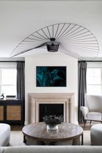 Load image into Gallery viewer, Living room featuring a striking piece of abstract art for sale titled 'Mingle IX' by Addison Jones Studio, displayed above a modern fireplace. The artwork showcases vibrant colors and artistic design, enhancing the room's decor. A sleek, circular coffee table with a floral centerpiece complements the elegant atmosphere.