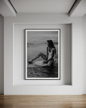 Load image into Gallery viewer, The artwork &#39;Riding Tide&#39; displayed elegantly in a modern room, featuring a woman in a white swimsuit on a surfboard, framed to complement contemporary decor.
